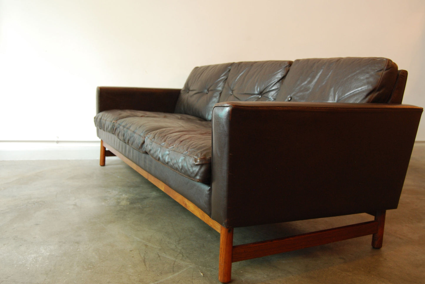 Three seat leather sofa on rosewood base
