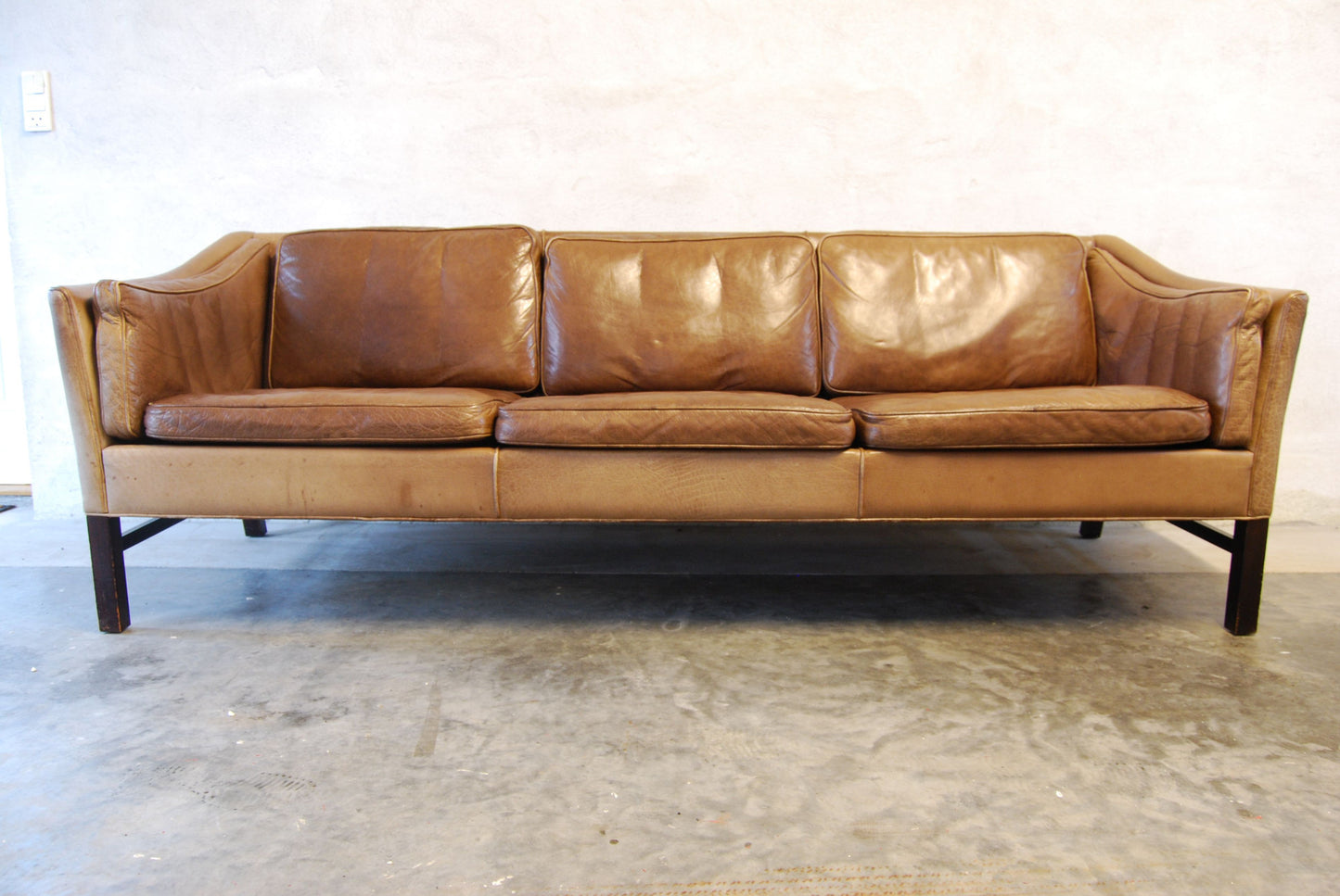 Three seat leather sofa with scalloped back