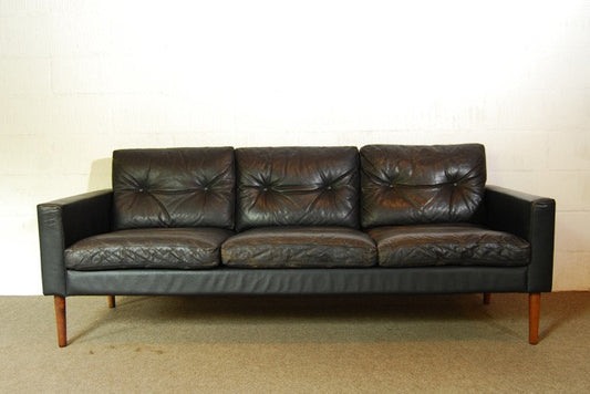 Black leather three seater on rosewood legs