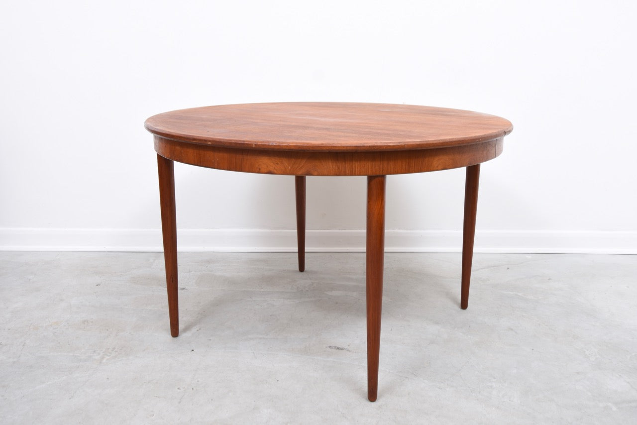 Extending round teak dining table